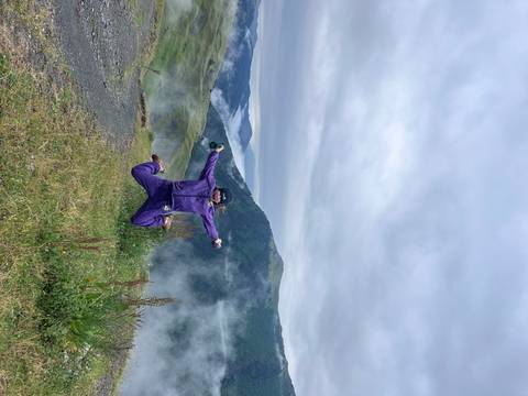       Person jumping with scenic mountain view in the background.
  