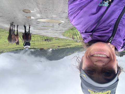 Person taking a selfie with a rural mountainous scene.