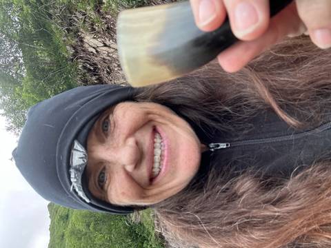       Person holding a beverage with misty mountain backdrop.
  