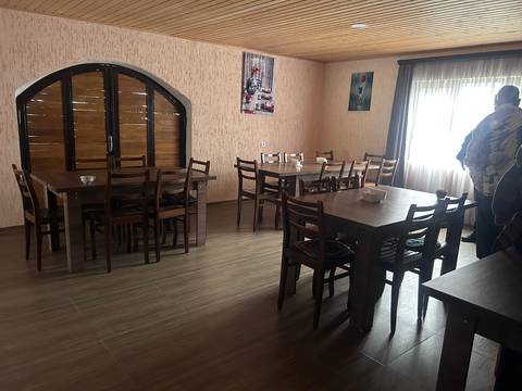       Simple dining area with tables and chairs by a window.
  