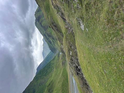 Green mountain valley under a cloudy sky.