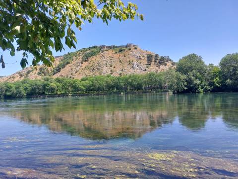       Hilltop fortress reflected in a clear river.
  