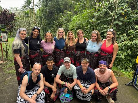       Group of tourists in sarongs in a lush jungle setting.
  