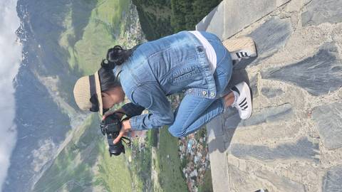       Woman photographing a mountainous landscape.
  