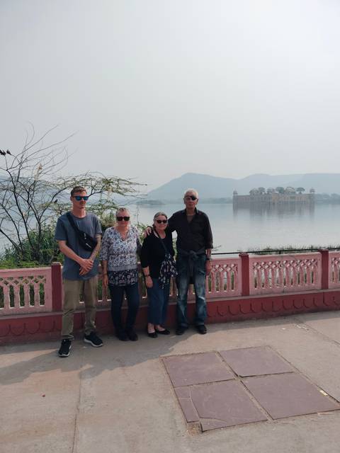 Group of people posing by a lake with a palace in the background.