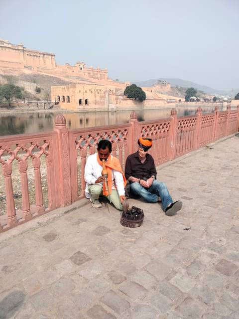 Two men sitting by a waterfront, one wearing a turban.