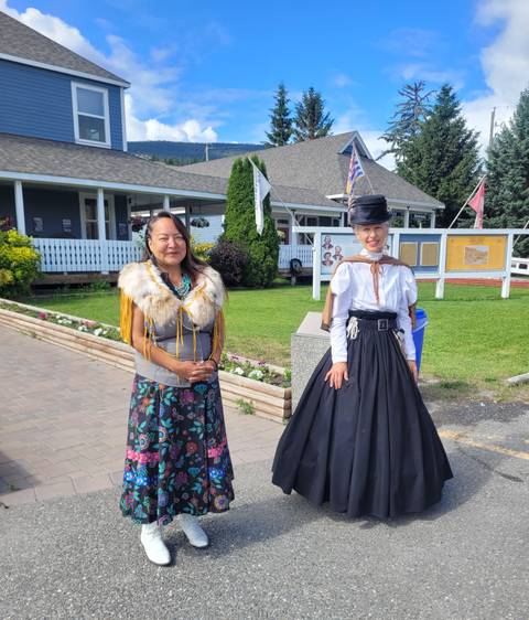 Two women in cultural attire posing in front of an attraction.
