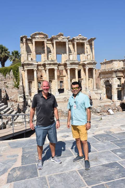 Two people standing in front of ancient ruins.