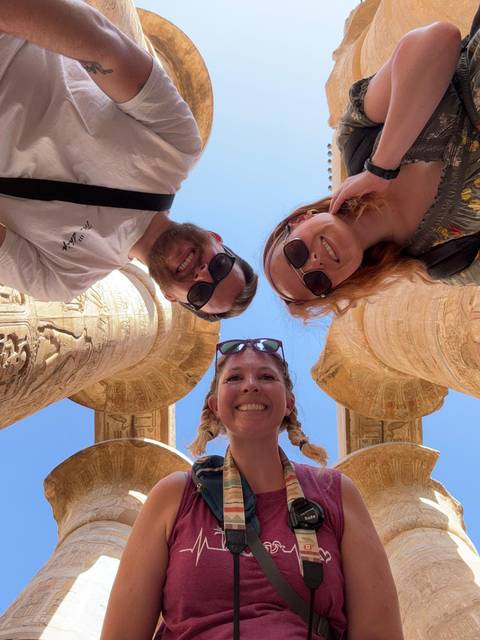 Group of people looking up at camera with ancient columns around.