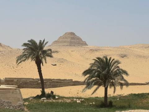 Pyramid-shaped structure with palm trees in the desert.