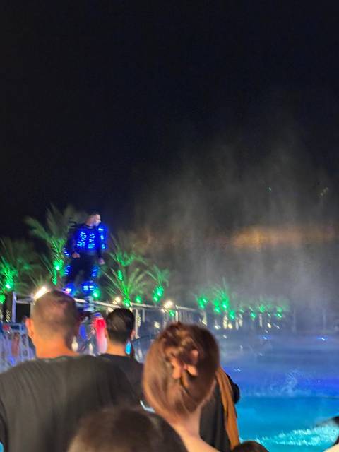 Blurry image of a person in LED clothing performing at night.
