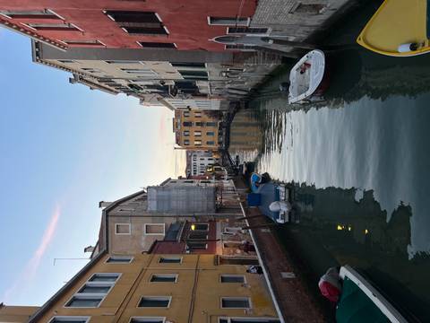 Venetian canal during early evening with boats and a small bridge.