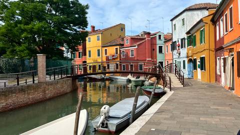      Colorful houses along a canal with a pedestrian bridge in the foreground.
  
