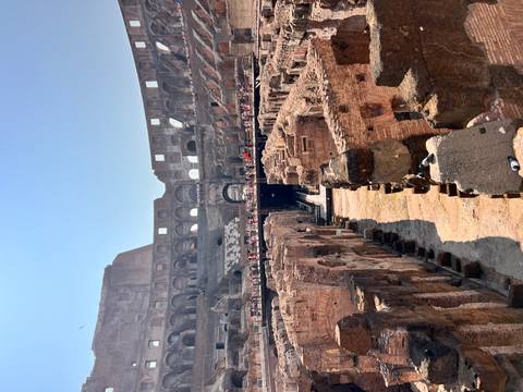 Central arena of the Colosseum with tourists walking on the lower level.