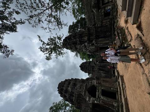 Couple posing in front of ancient ruins under a cloudy sky.
