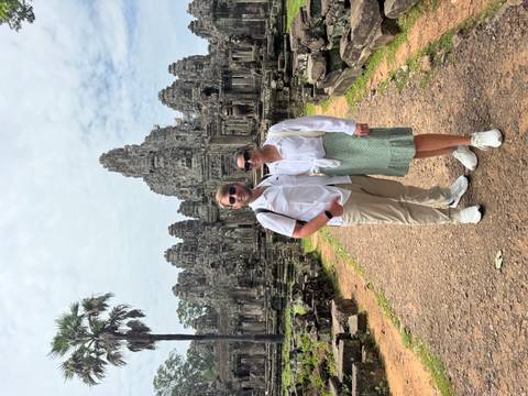 Couple posing in front of temple ruins with detailed carvings.