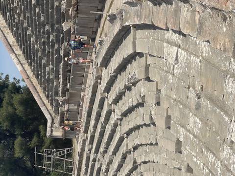       Ancient amphitheater with visitors exploring.
  