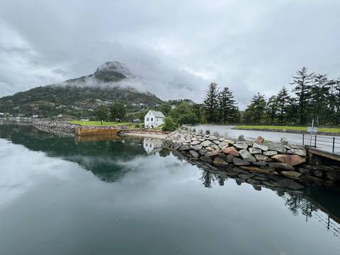       Mountain and village reflected in calm water.
  
