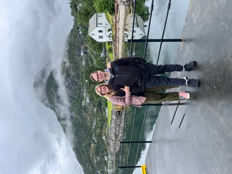       Couple posing with a mountainous background and reflection in the water.
  