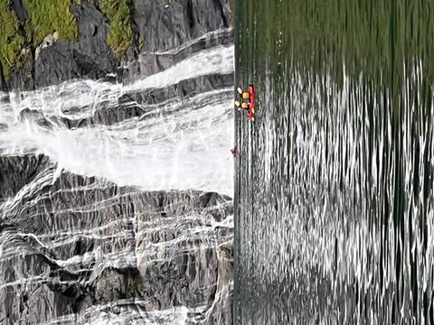       Waterfall cascading into a river with people kayaking.
  