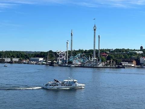       Amusement park across a body of water under a clear blue sky.
  