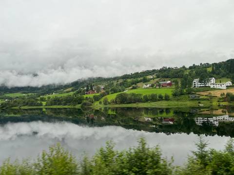       Lush valleys with reflections of houses in a calm river.
  