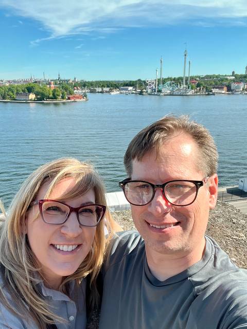       Couple posing with water in the background on a sunny day.
  