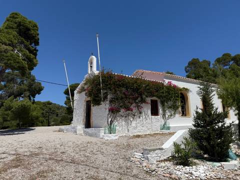       White chapel with flowers under a blue sky.
  