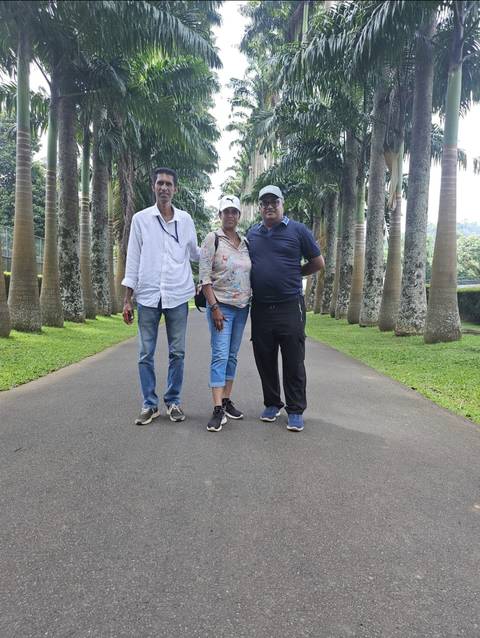       Three people posing on a path with palm trees.
  