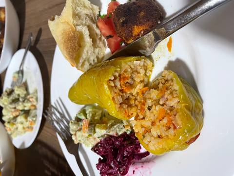       Stuffed pepper with other food items on a plate.
  