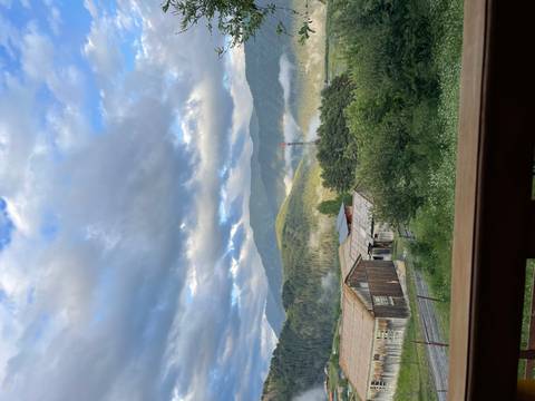 Scenic view of a rural area with mountains in the background and clouds.