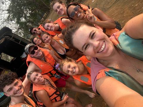       Group of people smiling and wearing life jackets outdoors.
  