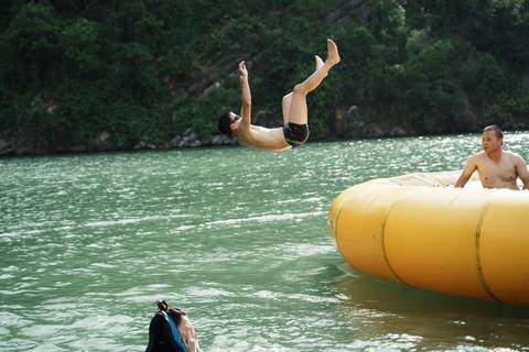 Two people near a floating platform on a lake, one diving mid-air.