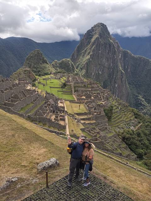 Panoramic view of Machu Picchu with a person in the foreground.