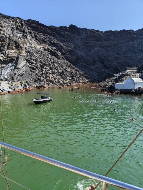 People swimming in a rocky inlet with a boat.