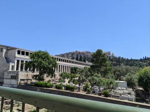 Historic Greek building with columns and ruins in foreground.