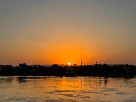       Sunset over a river with an orange sky.
  