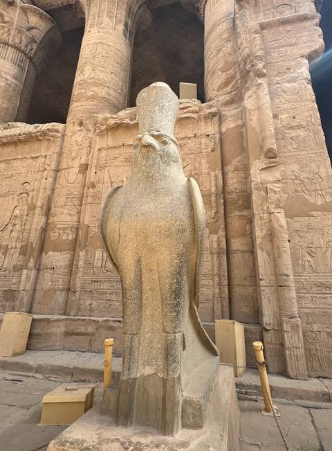       Stone statue of a falcon with hieroglyphics in the background.
  