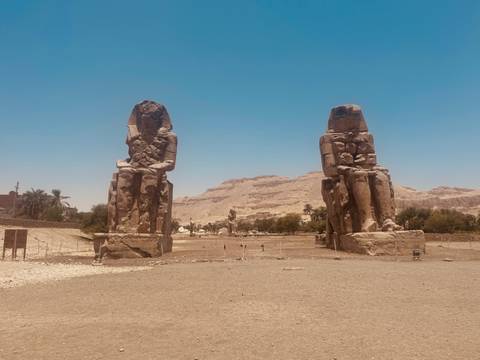       Two massive stone statues in a desert landscape.
  