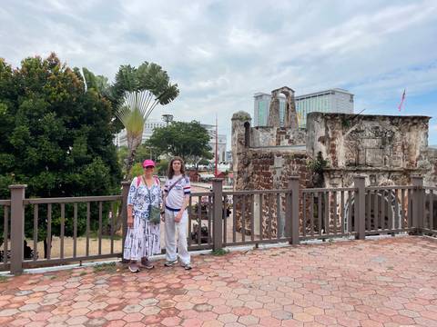 Tourists posing in front of an old stone fort with urban background.