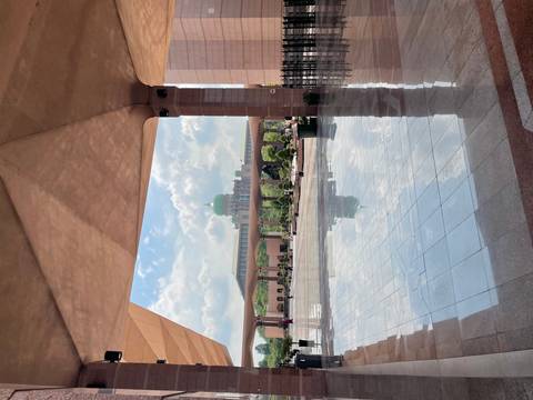 Distant view of a green-domed building through an archway.