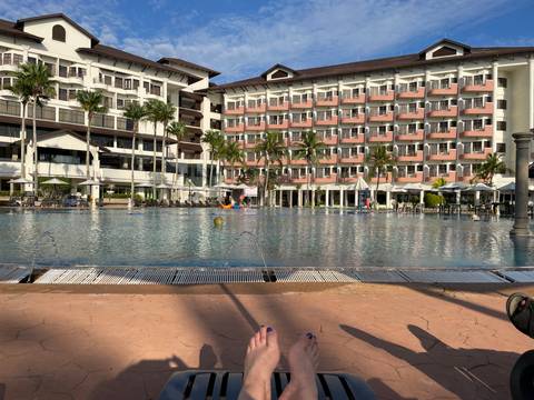 Large hotel with swimming pool and lounge chairs.