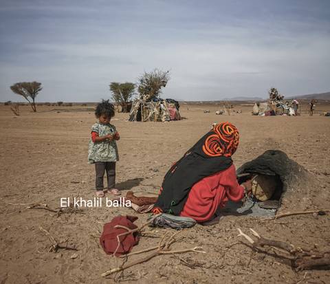       Outdoor scene with people and children in the desert.
  