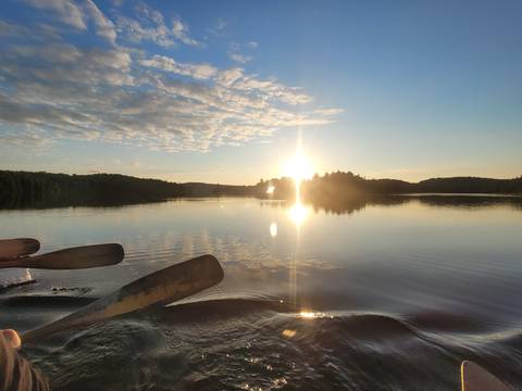 Paddle in a canoe with a sunset over a still lake.