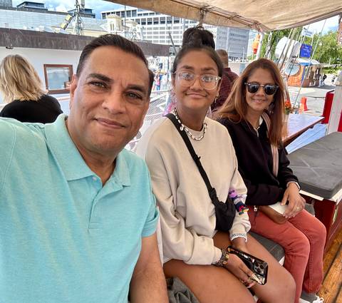 Three people sitting on a boat, smiling at the camera.