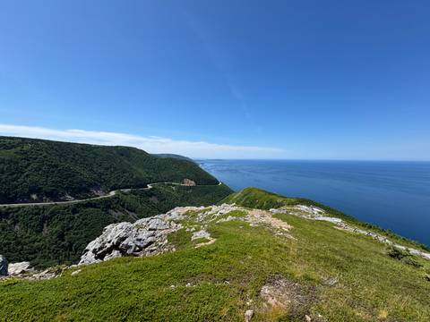       Expansive coastal view with cliffs and a winding road.
  