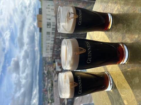 Three pints of Guinness on a table with city view.
