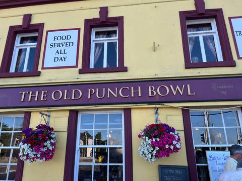 The Old Punch Bowl pub with signs and flowers.