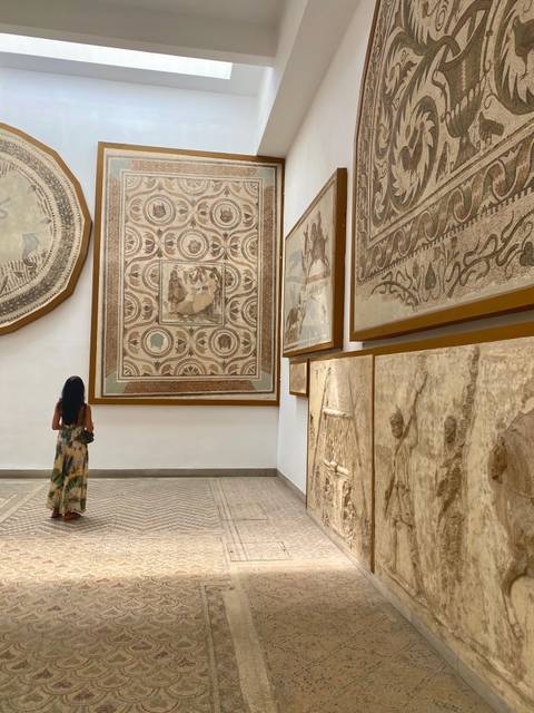 A woman observing intricate mosaics and artwork on the walls.