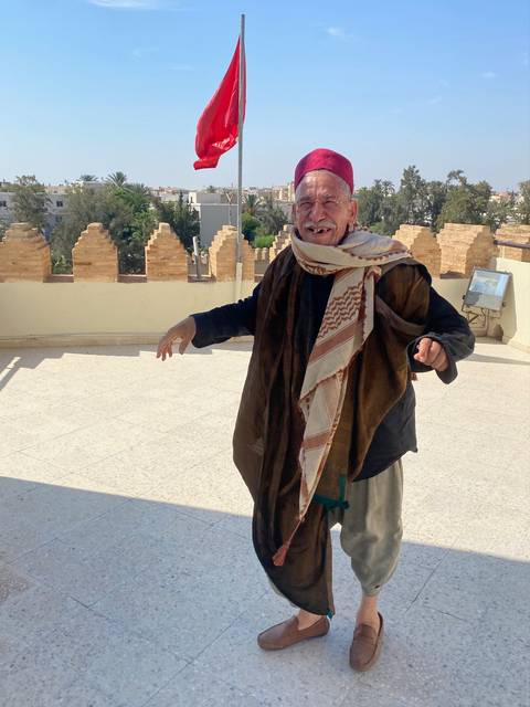 A man in traditional attire standing outdoors.